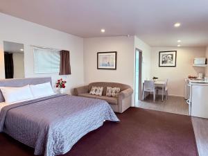 a bedroom with a bed and a couch and a table at Morrinsville Motel in Morrinsville +44 photos