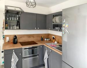 a kitchen with gray cabinets and a stainless steel refrigerator at Appartement charmant à Six-Fours-les-Plages avec jardin in Six-Fours-les-Plages +9 photos