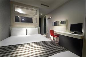 ein Hotelzimmer mit einem Bett und einem Schreibtisch mit einem TV in der Unterkunft Sotetsu Fresa Inn Shimbashi-Karasumoriguchi in Tokio