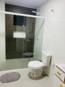 a bathroom with a toilet and a glass shower at Apartamento caminho das thermas in Piratuba