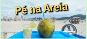 a drink and a coconut on a blue tray on the beach at Pé na Areia Gonzaguinha Perto de Tudo in São Vicente