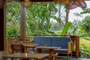 a patio with a blue couch and tables at Emana Akatara in Ubud