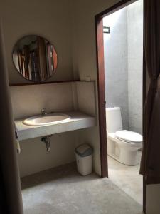 a bathroom with a sink and a mirror and a toilet at Fern House Retreat in Chalong