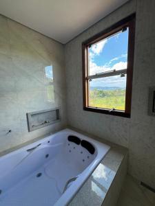 a large white bath tub in a bathroom with a window at Hotel Boutique Canto da Seriema in Tiradentes +55 photos