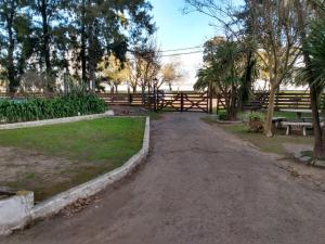 a dirt road in a park with benches and trees at El Viejo Roble in Chascomús