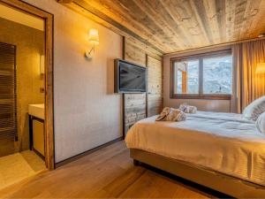 ein Schlafzimmer mit einem Bett, einem Fernseher und einem Fenster in der Unterkunft Duplex Spacieux au Rond-Point des Pistes avec Parking, Balcon et Services Inclus - FR-1-613-93 in Les Allues