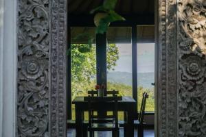 a dining room with a table and a large window at Temuku Pupuan Farmstay in Padangan