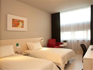 a hotel room with two beds and a red chair at Jinjiang Inn Fuzhou Cangshan Olympic Centre in Fuzhou