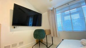 ein Schlafzimmer mit einem TV an der Wand und einem grünen Stuhl in der Unterkunft 1 Bedroom, Near Alexandra Palace - London - Kings Cross - New Southgate Suite 1 in New Southgate