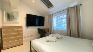 ein Schlafzimmer mit einem Bett, einem Fernseher und einem Fenster in der Unterkunft 1 Bedroom, Near Alexandra Palace - London - Kings Cross - New Southgate Suite 1 in New Southgate + 3 Fotos