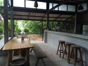 a wooden table and stools in front of a bar at Fern House Retreat in Chalong