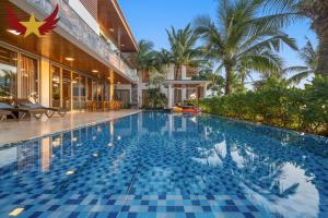 a swimming pool in front of a house at The Five Stars Villa 8 Bedrooms Beachfront in Danang