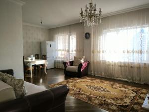 a living room with a couch and a chandelier at 3-х комнатная квартира, кухня-студия in Astana