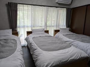 three beds in a room with a window at 奥阿蘇のあかまつ in Aso