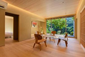 a living room with a table and chairs and a large window at Kinshuusanso in Kawaba