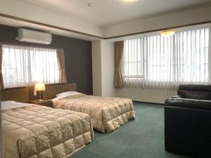 una camera d'albergo con due letti e un divano di Itoen Hotel a Ito Altre 37 foto