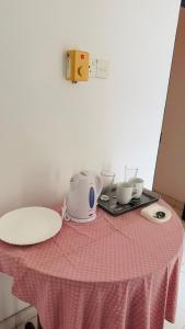 a table with a pink table cloth with a tea set on it at Relax Home in Sri Jayewardenepura Kotte