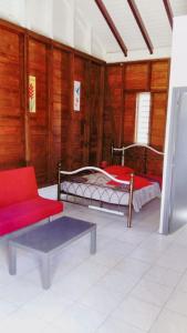 a living room with two beds and a red couch at Bungalow charmant à Château Gaillard avec piscine partagée in Le Moule +11 photos