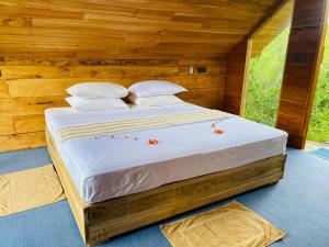 a bed in a wooden room with flowers on it at Mamba Yala in Tissamaharama +143 photos