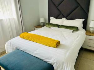 a large white bed with a yellow blanket on it at Out of Ordinary 3beds BKT Plot 15298 in Gaborone
