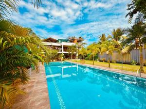 a swimming pool in front of a house with palm trees at Dharma Place in Ahangama
