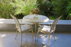 a table with two chairs and a vase of flowers on it at Pecan Tree Forest Studio B with Terrace in Stellenbosch