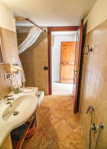 ein Badezimmer mit Waschbecken und Holztür in der Unterkunft Stonehouse apartments in Forcella