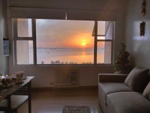 a living room with a large window with a sunset at Chic Haven in Manila