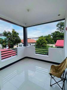 a white balcony with a chair and large windows at H&D Dumaguete Apartment in Dumaguete