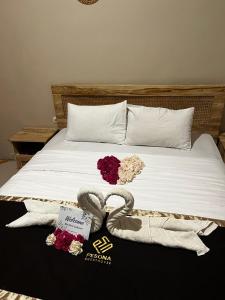a bed with two towels and flowers on it at Pesona Guesthouse Syariah Malang in Kotalama