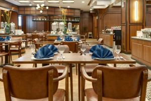 un restaurante con mesas de madera y sillas con servilletas azules en Hotel Pangeran, en Pekanbaru