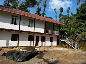 a white building with a porch and stairs in front at Birdsong Coffee Estate Stay in Madikeri