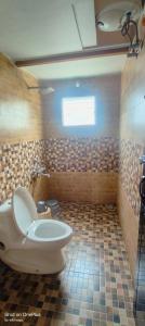 a bathroom with a toilet and a tiled floor at Wild ways home stay kothagiri in Kotagiri
