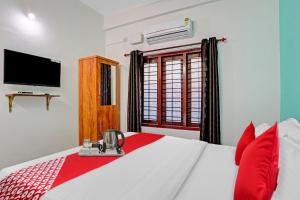 a bedroom with a bed with red pillows and a television at Hotel O Bevis in Trivandrum
