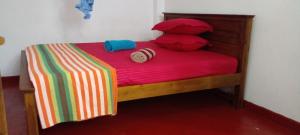韦利格默Sriya Family Villa Weligama的一张带红色毯子和枕头的小床