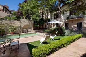 un cortile con piscina, sedie e ombrellone di L’Arco Romanico a Montefalco