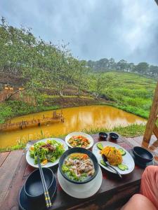a table with plates of food and a view of a river at Thôn Yên Glamping in Xuan An