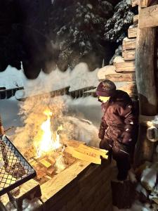a person standing next to a camp fire at Rukanmetsä, cottage, Ruka in Rukatunturi 