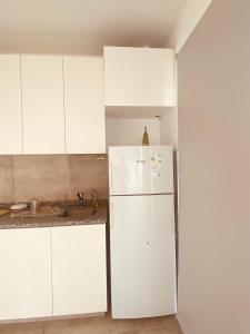 a kitchen with a white refrigerator and white cabinets at Aires del este in Arroyito +4 photos