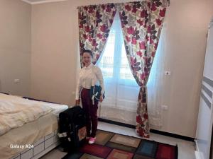 a woman standing in front of a window with a suitcase at Valencia Villa & Rooms in Luxor