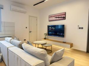 a living room with a white couch and a flat screen tv at Masaki Haven in Dar es Salaam
