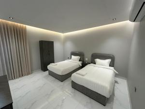 two beds in a room with white walls at شقة مفروشة بمنطقة هادئة in Makkah