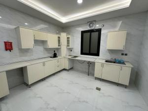 a kitchen with white cabinets and a large tile floor at شقة مفروشة بمنطقة هادئة in Makkah