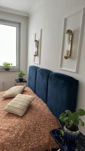 a bedroom with a bed with blue chairs and a plant at Celine Apartments in Lębork