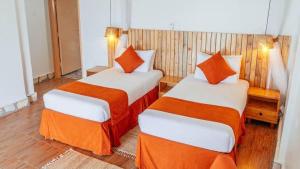 a bedroom with two beds with orange and white sheets at Acacia Wilderness Mweya in Kasese