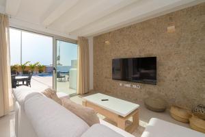 Una sala de estar con un sofá blanco y un televisor. en Villa Santorini, en San Fulgencio