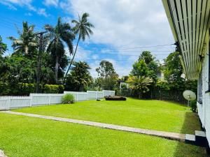 a yard with a white fence and green grass at Cozy 3BR Wooden Retreat in Suva