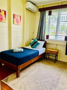 a bedroom with a bed with blue sheets and a window at Cozy 3BR Wooden Retreat in Suva