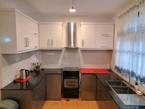 a kitchen with white cabinets and a stove top oven at Tharan Villa - House in Colombo in Polgasowita
