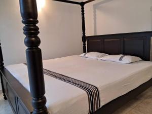 a bed with a black bed post with two pillows at Tharan Villa - House in Colombo in Polgasowita +38 photos